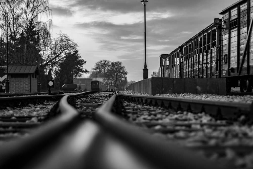 Czarno-białe zdjęcie torów kolejowych i wagonów.